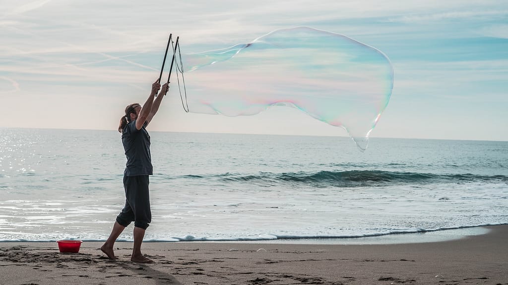 Man blowing large bubbles at the beach
